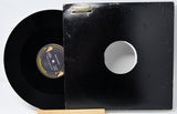 Vinyl record with a white label on a black sleeve, displayed on a stand.