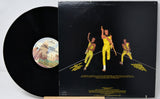 Vinyl record with a cover featuring three people in yellow outfits on a black background.