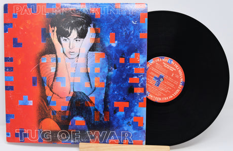 Vinyl record with colorful cover featuring a person and text 'Tug of War' by Paul McCartney.