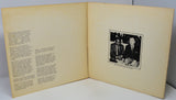 Open book with text on one page and a black and white photo of two men on the other, against a gray background.