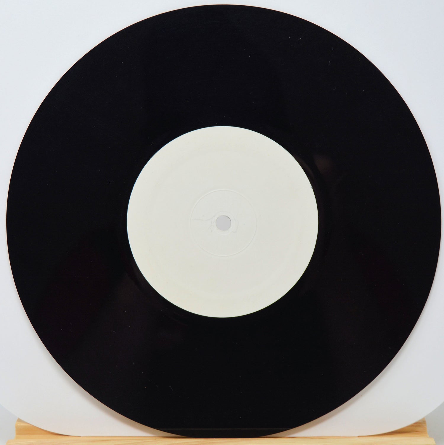 Black vinyl record with a white label on a light gray background