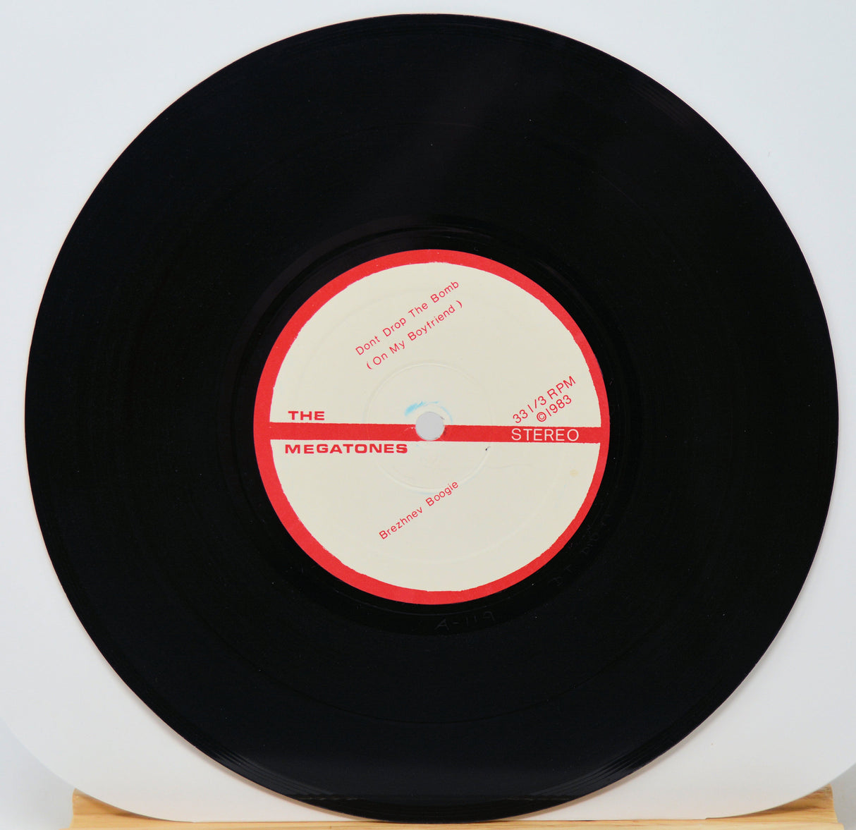 Vinyl record with a red and white label on a light gray background
