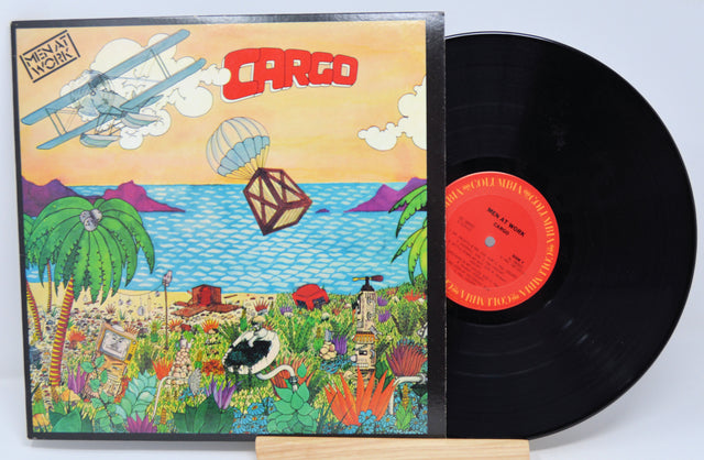 A vinyl record titled 'Men At Work - Cargo' with a colorful album cover featuring illustrations of a plane, landscape, and animals.