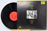 Vinyl record with black cover featuring a group photo and text on a white background