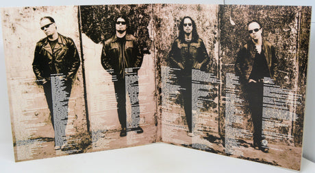 A square printed art piece or poster showing four vertically aligned black-and-white portraits of a band member, overlaid with horizontal columns of small text, photographed against a plain light background.