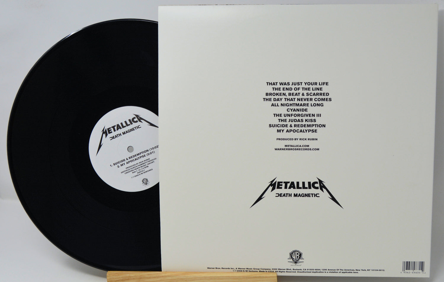Metallica's 'Death Magnetic' vinyl record shown with its outer sleeve, featuring the black record partially pulled from the white sleeve with tracklist text and the Metallica logo.