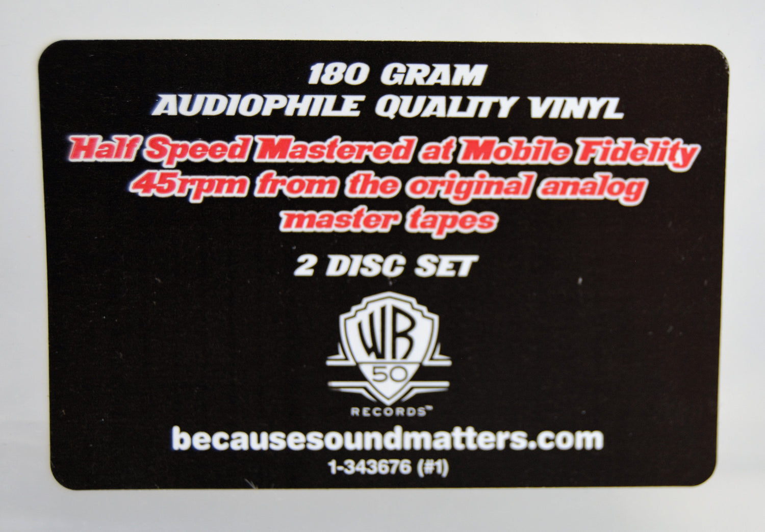 A black rectangular sticker for a 180 gram audiophile quality vinyl 2 disc set. The card features white and red text detailing the mastering and speed, along with the Warner Bros.