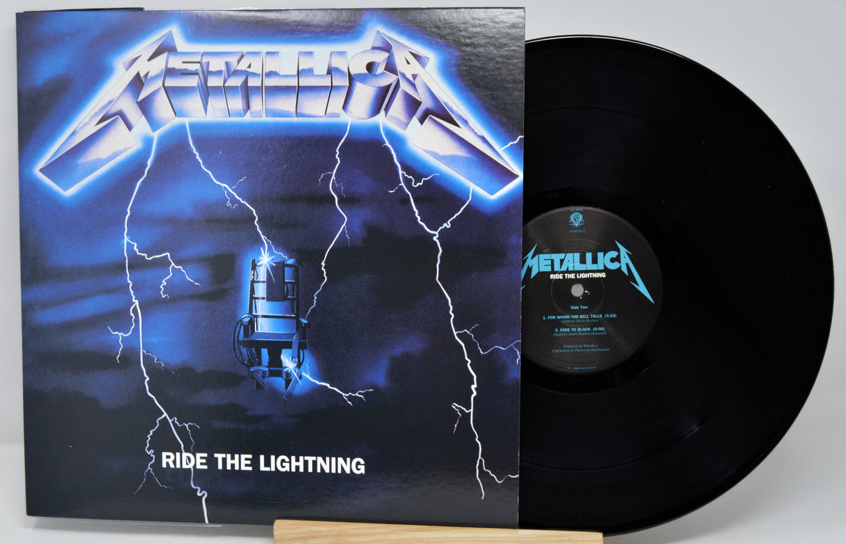 Metallica's 'Ride the Lightning' vinyl record album with the black LP partially pulled from the sleeve, photographed on a light gray background.