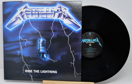 Metallica's 'Ride the Lightning' vinyl record album with the black LP partially pulled from the sleeve, photographed on a light gray background.