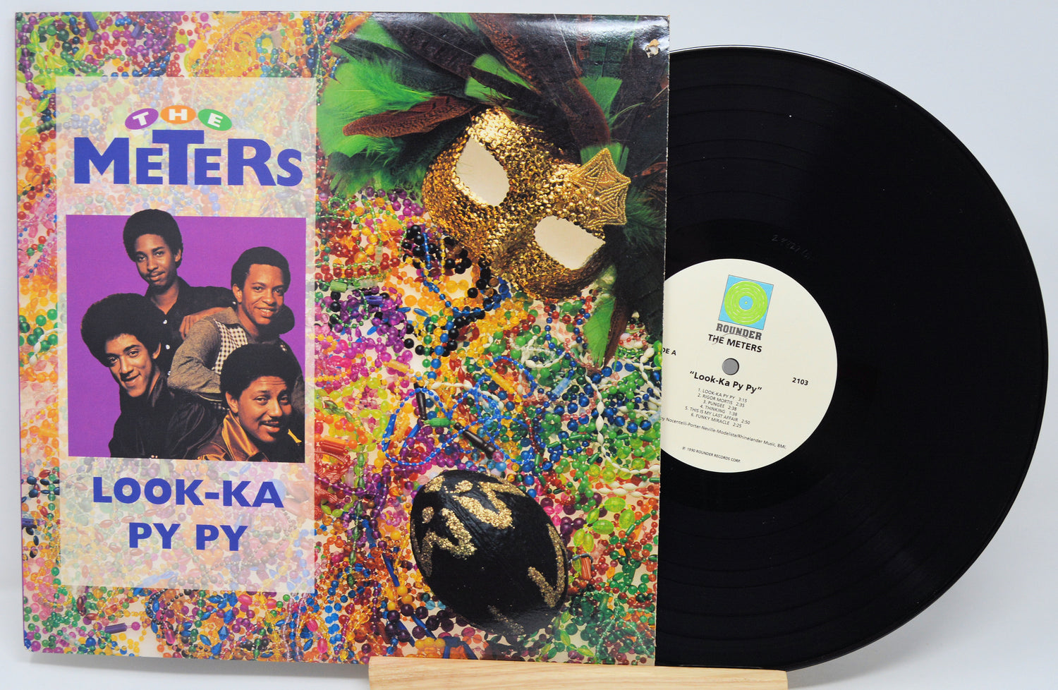Vinyl record with colorful cover featuring images of people and text.