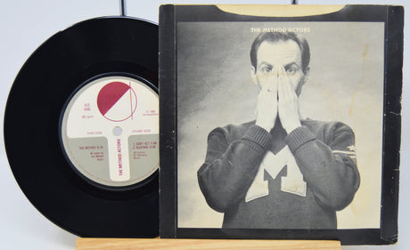 Vinyl record and its cover featuring a person with their hand over their face on a white background