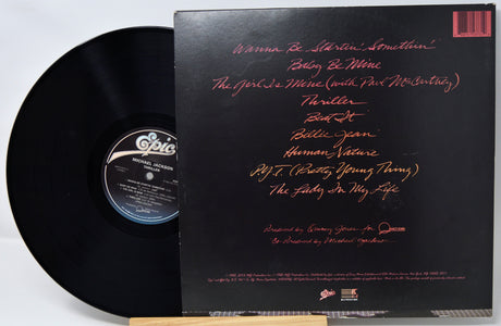 Vinyl record with a black cover featuring red text on a white background