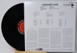 A vinyl record partially pulled from its printed back cover, showing the black record with a red-and-black Columbia label and the white insert printed with track listings and text. The title 'LEGRAND JAZZ' and 'COLUMBIA' are visible.