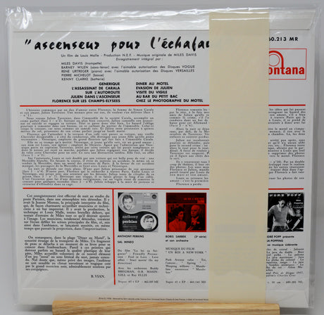 A vintage French movie program booklet for the film 'Ascenseurs pour l'échafaud' (Towers for the Dying) from 1963, displayed on a small wooden stand. The booklet features black text columns, two black-and-white photos of actors, and the red and white 'Montana' publisher logo at the top right.