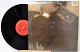 Vinyl record with a black disc and red label, and a cover featuring a person in a helmet.