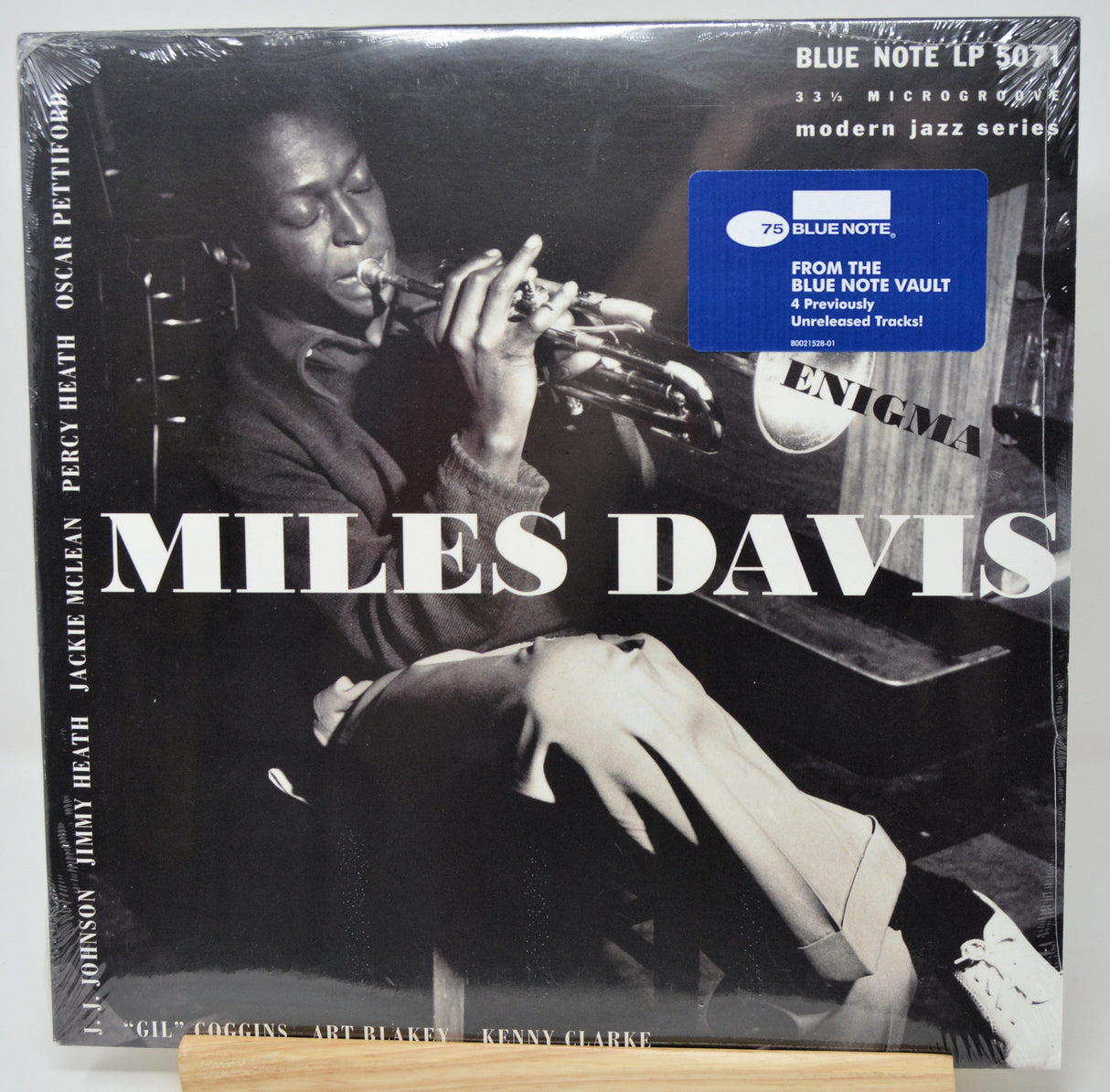 Miles Davis LP album cover on a wooden surface, showing a black-and-white photo of the trumpet player with large white 'MILES DAVIS' text and a blue Blue Note sticker.