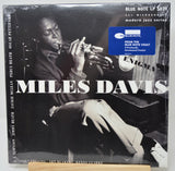 Miles Davis LP album cover on a wooden surface, showing a black-and-white photo of the trumpet player with large white 'MILES DAVIS' text and a blue Blue Note sticker.