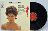 Miles Davis 'Someday My Prince Will Come' vinyl record with the album cover standing beside the black record disc on a light gray background.