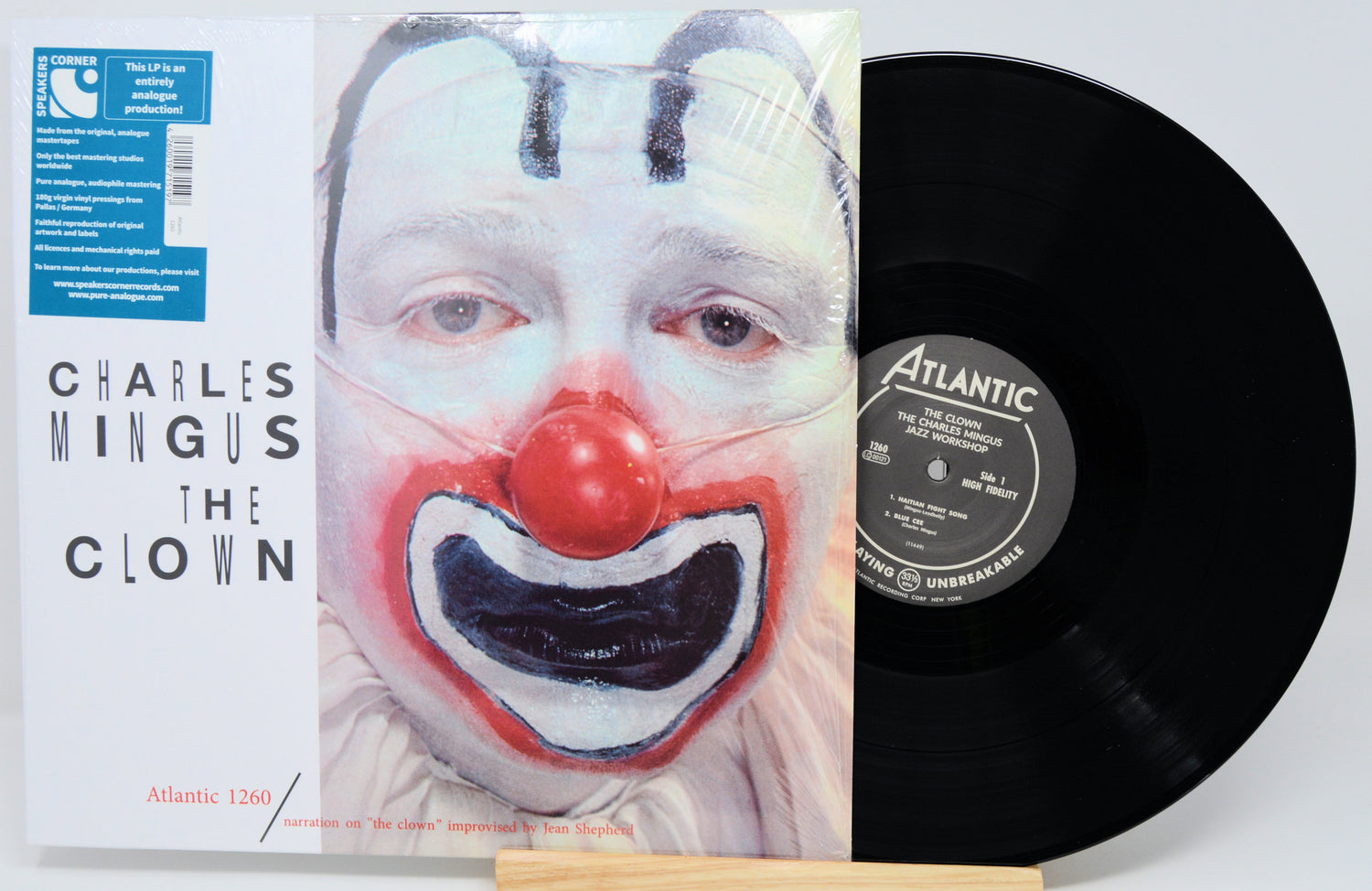 Charles Mingus 'The Clown' vinyl record LP with its illustrated cover and a black record partially visible, photographed on a light gray background.