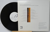 Vinyl record with its cover displaying text and a logo on a light gray background
