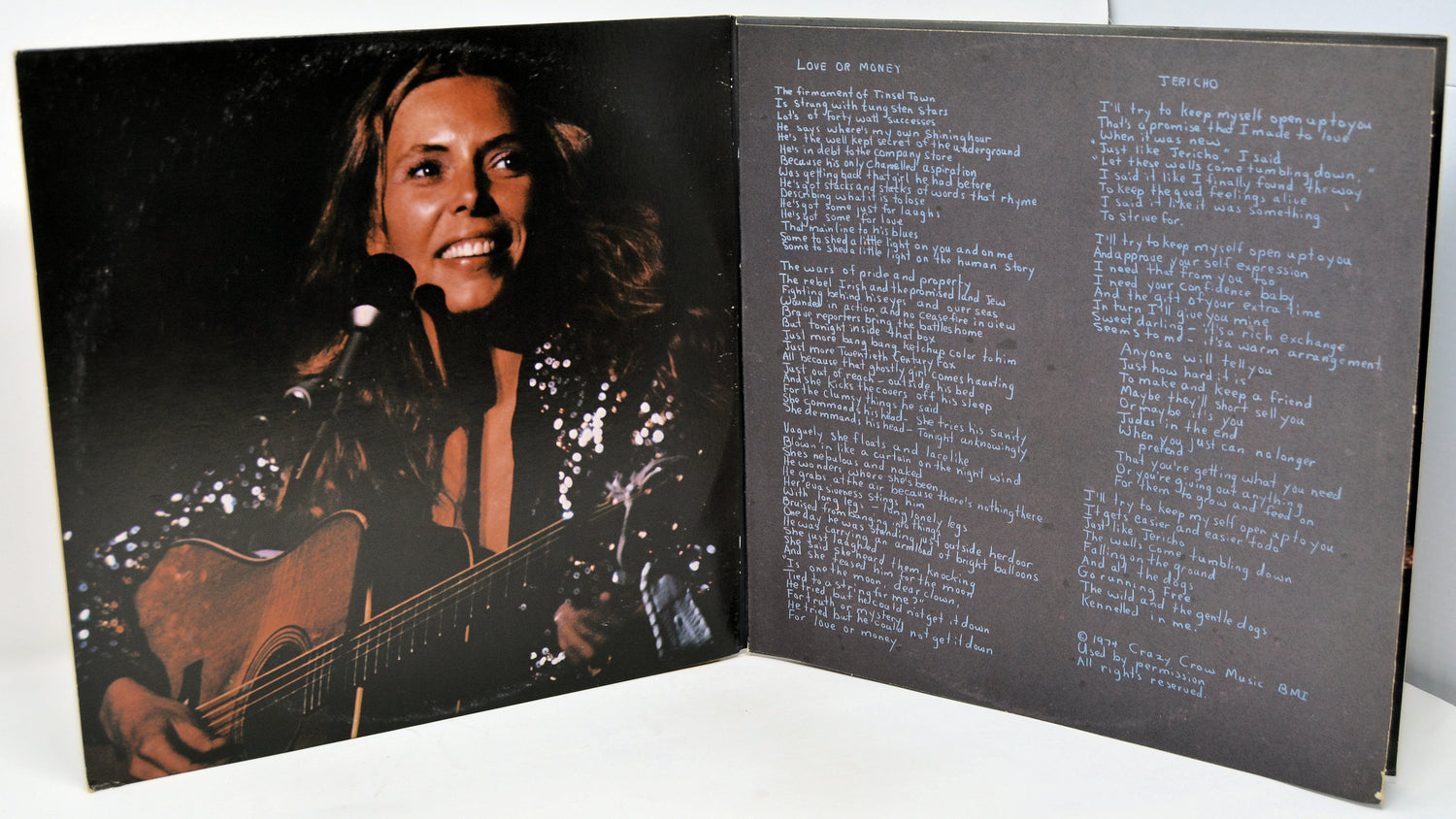 Album cover with a person playing guitar and song lyrics on a black background