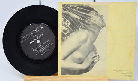 Vinyl record with a black label and a yellowed cover featuring a nude figure.