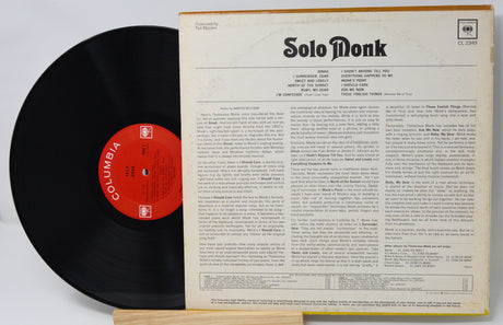 Vinyl record with red label and cover displaying text on a light gray background