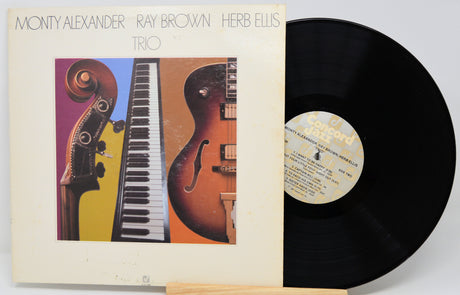 Monty Alexander, Ray Brown, and Herb Ellis Trio vinyl record LP with the album cover standing next to the black record on a stand.