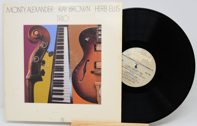 Monty Alexander, Ray Brown, and Herb Ellis Trio vinyl record LP with the album cover standing next to the black record on a stand.