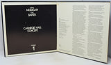 An open book or program booklet showing the front cover on the left with a black background and white text reading 'Gerry Mulligan and Bart Baker Carnegie Hall Concert Volume 1,' and printed text pages on the right.