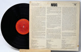 A vintage NRBQ vinyl record shown with its back cover standing upright behind it. The black record partially overlaps the cover, and the center label is orange-red with printed text.
