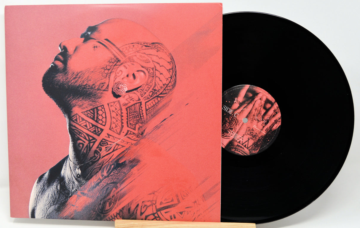 Vinyl record with a cover featuring a tattooed person on a red background