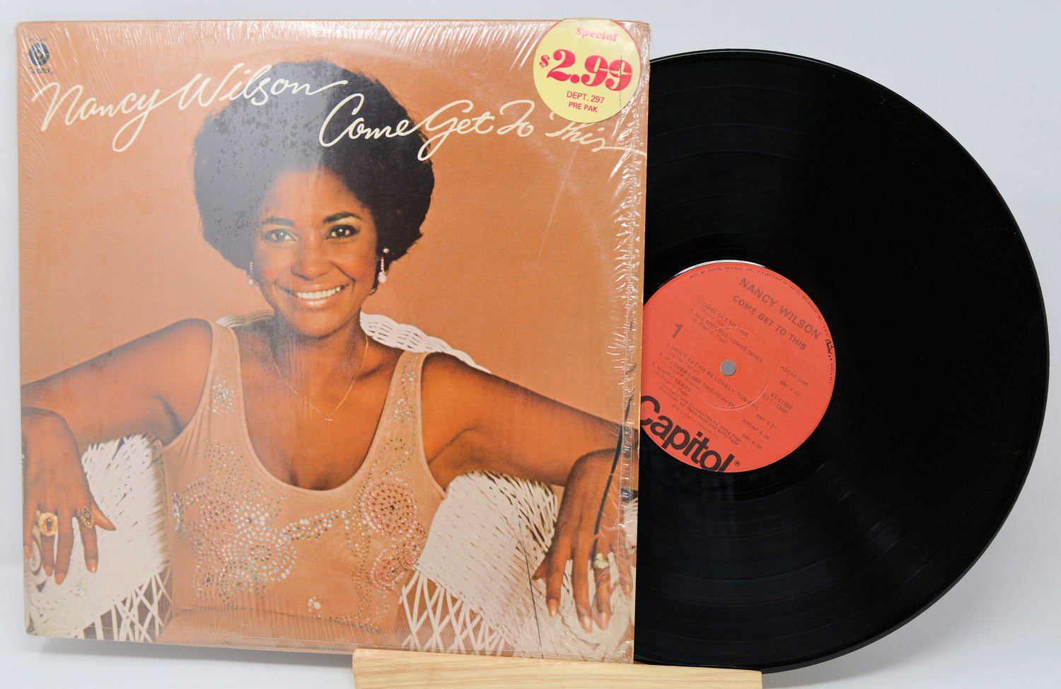 Vinyl record with cover featuring a woman, on a light gray background