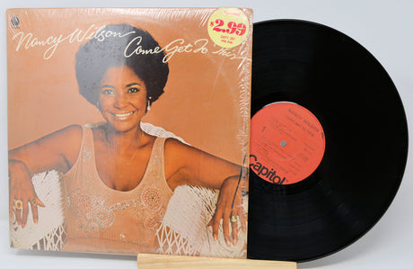 Vinyl record with cover featuring a woman, on a light gray background