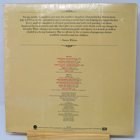 Back cover of a vinyl record with text and tracklist on a beige background