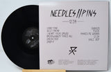 Vinyl record with 'Needles//Pins' album cover on a light gray background