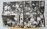 Black and white photo album open to a page with multiple images of people in a crowded room.