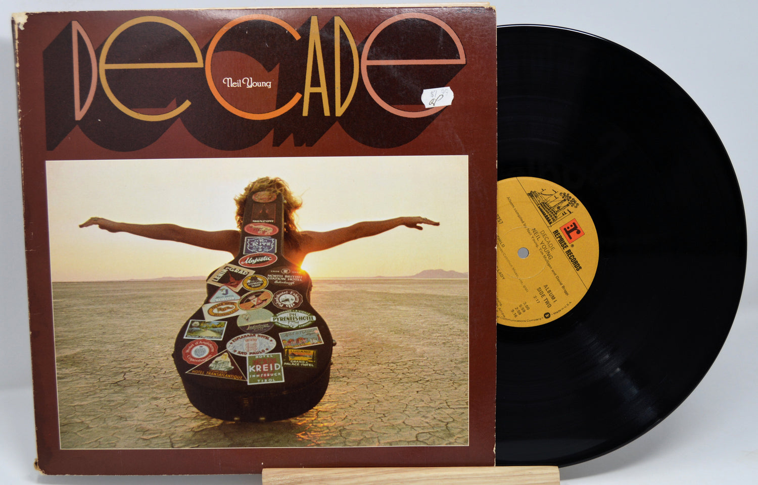Vinyl record with cover featuring a person holding a guitar made of license plates, set against a desert landscape.