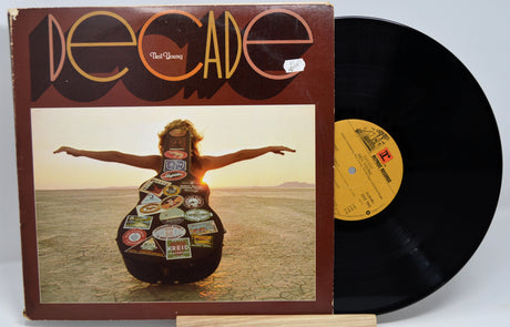 Vinyl record with cover featuring a person holding a guitar made of license plates, set against a desert landscape.