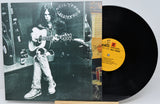 Neil Young's 'Greatest Hits' vinyl record album, showing the black-and-white cover jacket on the left and the black LP record partially pulled out on the right with a yellow label.