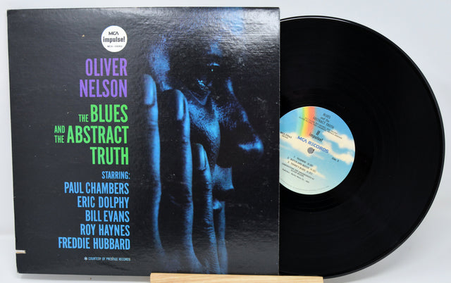 Vinyl record with cover featuring text and a hand silhouette, on a white background