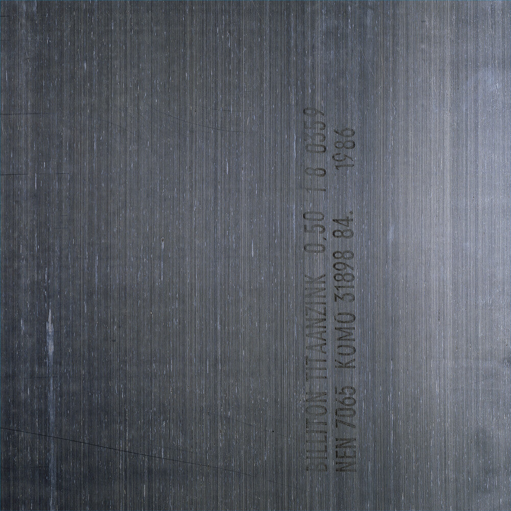 A close-up of a dark gray metallic surface with fine horizontal brushed texture and vertical stamped text.