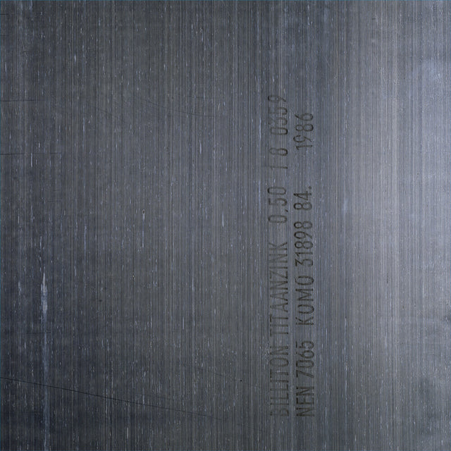 A close-up of a dark gray metallic surface with fine horizontal brushed texture and vertical stamped text.