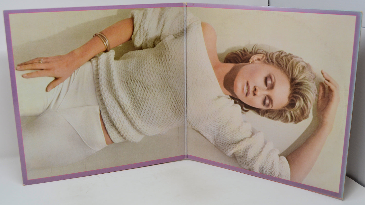 Open book showing a woman wearing a white knitted sweater on a plain background