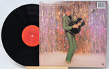 Vinyl record with a colorful album cover featuring a person playing guitar against a glittery curtain.