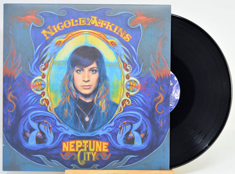 A vinyl record partially pulled from its illustrated album sleeve. The cover art features a portrait of Nicole Atkins with the text 'Nicole Atkins' at the top and 'Neptune City' at the bottom.