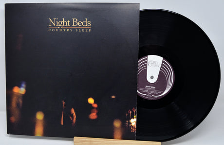 Vinyl record with cover titled 'Country Sleep' by Night Beds on a blurred background.