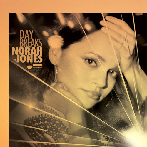 Album cover for Norah Jones's 'Daybreaks' featuring a sepia-toned portrait of the artist behind a wire-like barrier, with the title and artist name printed on the left.