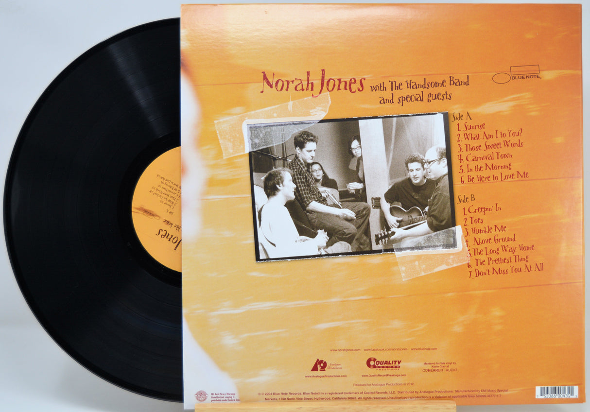 Norah Jones vinyl record LP shown with the black record partially pulled from the back cover, which has an orange and beige abstract design with a black-and-white band photo and tracklist.