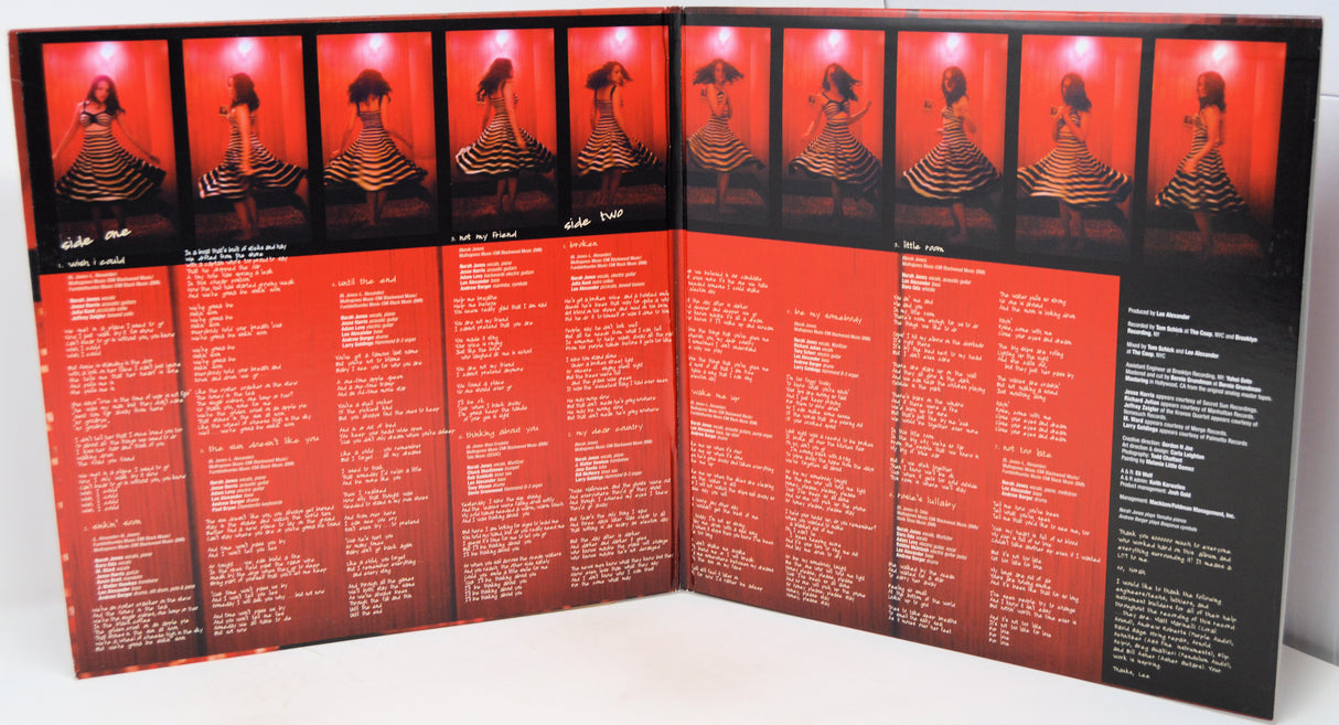 A large printed booklet or album-style spread with multiple red and black panels, each showing a woman in a striped dress from behind, with dense text blocks below. No person is physically present in the photographed scene; the visible figures are part of the printed material.